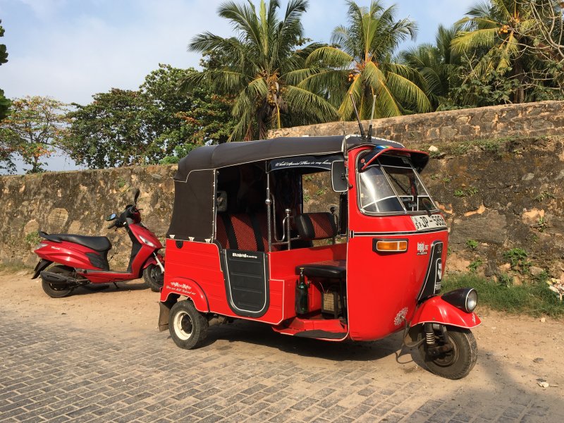 Red vehicles agains city wall, Galle